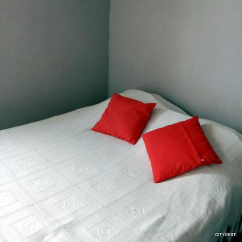 - un lit avec 2 oreillers rouges dans l'établissement Appartement T3 proche commerces et animations - 5CDUSUD1, à Canet