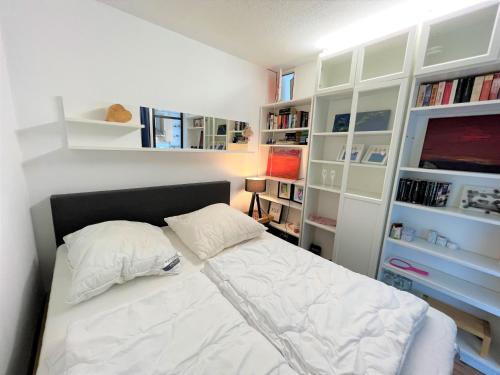 Habitación pequeña con cama blanca y estanterías. en Panoramic App A03-5, en Sierksdorf