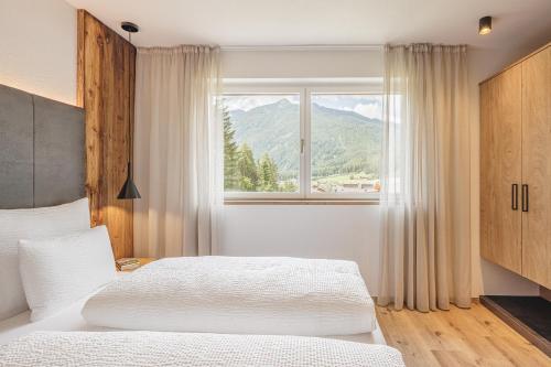 een slaapkamer met een bed en een raam met uitzicht op de bergen bij Apartments Silva Mountain in San Giovanni in Val Aurina
