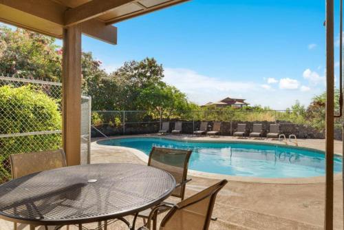 a patio with a table and chairs and a pool at Kona Mansions by Casago Kona - Condo C-108 in Kailua-Kona