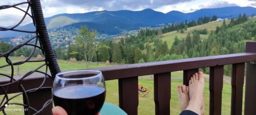 a person sitting on a balcony with a glass of wine at Мелодія Гір Вид на гори in Vorokhta