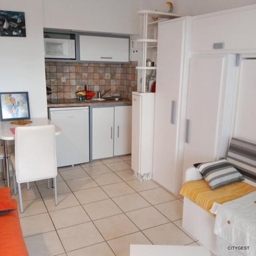 une cuisine avec des armoires blanches et une table dans une pièce dans l'établissement Studio 2 personnes proche Plage et Commerces - 2phoe504, à Canet