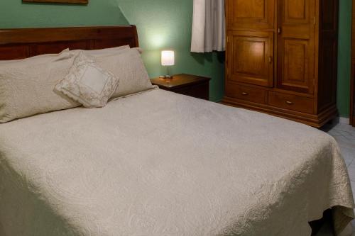 a bedroom with a white bed and a wooden cabinet at Hotel Gran Domo in León