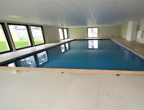 a large swimming pool with a tile floor and windows at Appartement cosy in Métabief