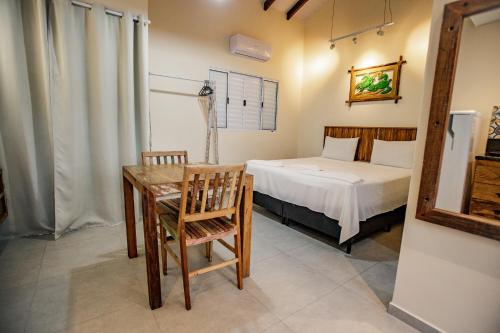 a bedroom with a bed and a table and chair at Flats de Sumatra in Boicucanga