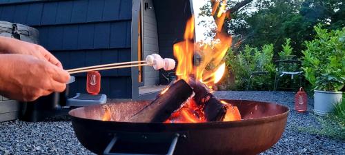 a man is cooking food in a pan with chopsticks at Odli Glamping - Deri in Welshpool