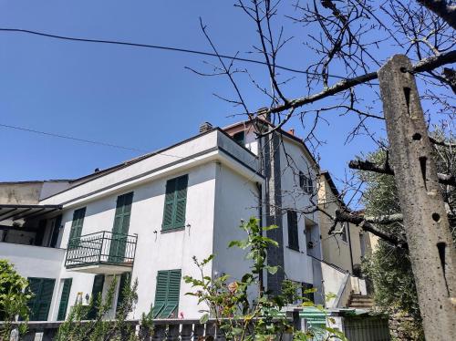 un antiguo edificio blanco con persianas verdes en La scala di Ba, en Castiglione Chiavarese