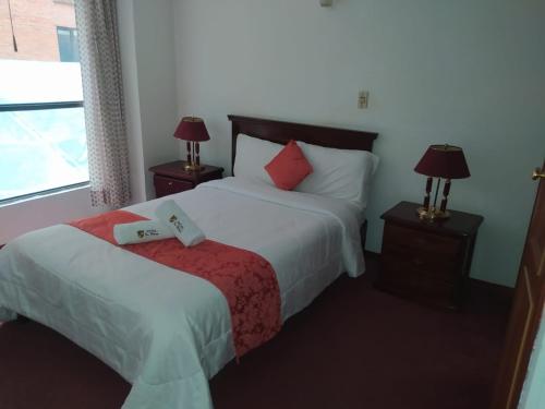 a bedroom with a bed with two lamps and a window at HOTEL REALPICO VICTORIA in Duitama