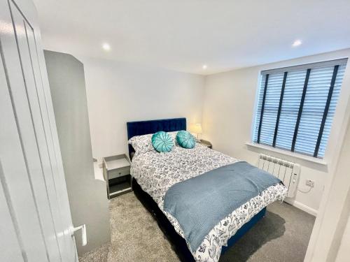 a bedroom with a bed with a blue headboard and a window at New Modern Apartment With FREE Private Parking in Plymouth