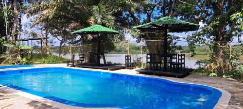 una piscina con due sedie e ombrelloni di Eco Hotel Aldea -AMAZONAS a Puerto Nariño