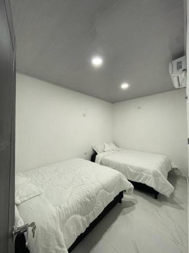 2 camas en una habitación con paredes blancas en Wamaris Plus Apt, en Mompós