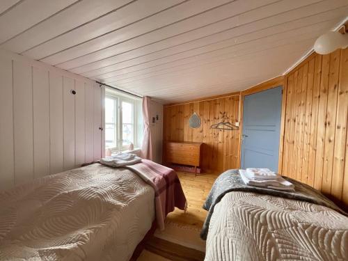 a bedroom with two beds in a room with wooden walls at Stamsund Authentic Rorbu in Stamsund