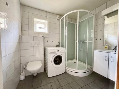 a bathroom with a washing machine and a shower at Stamsund Authentic Rorbu in Stamsund