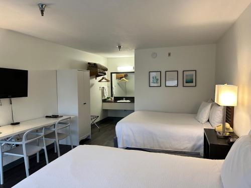 ブランソンにあるSeven Gables Innのベッド2台、デスク、テレビが備わるホテルルームです。