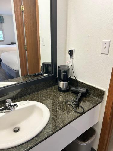 a bathroom counter with a sink and a coffee maker on it at Seven Gables Inn in Branson