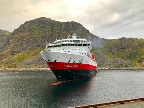 a red and white cruise ship in the water at Stamsund Authentic Rorbu in Stamsund