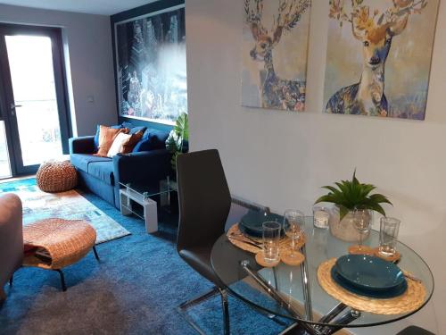 sala de estar con mesa de cristal y sofá azul en Northern Lights Apartment, en Saltaire