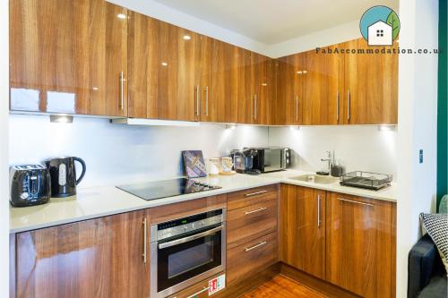 cocina con armarios de madera y microondas en Amazing Flat-Parking available-By FabAccommodation, en Cardiff