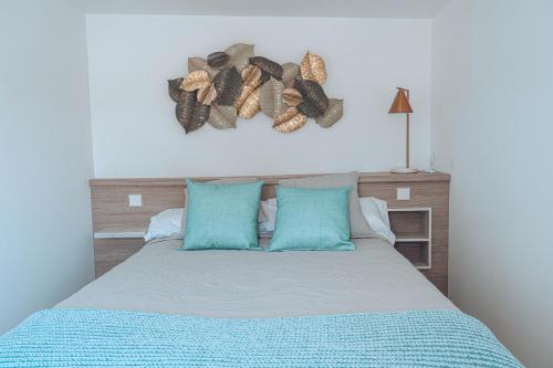 Schlafzimmer mit einem Bett mit blauen Kissen und einem Kopfteil in der Unterkunft Apartamentos La Moneda in Burgos