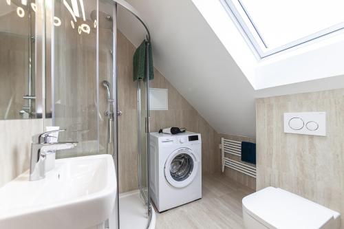 ein Badezimmer mit einer Waschmaschine und einem Waschbecken in der Unterkunft Attic Apartment with Peaceful view + Parking in Prag
