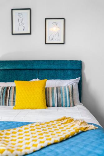 a bed with a blue head board and yellow pillows at Stylish 4 Bed-Town Centre in Galashiels