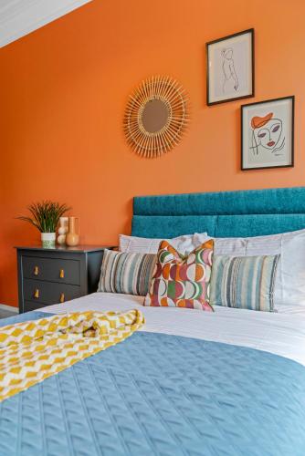 a bedroom with a blue bed with an orange wall at Stylish 4 Bed-Town Centre in Galashiels