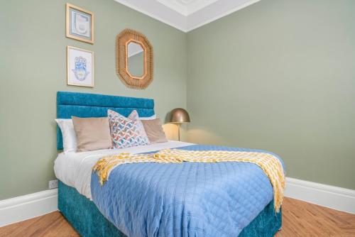 a blue bed with a blue comforter and a mirror at Stylish 4 Bed-Town Centre in Galashiels
