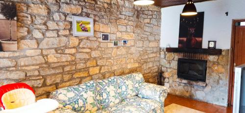 uma sala de estar com um sofá e uma parede de pedra em HABITACIONES PRIVADAS - CASA RURAL - Baño compartido con los anfitriones em Suances