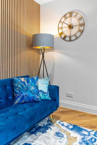 a blue couch in a living room with a clock at Stylish 4 Bed-Town Centre in Galashiels