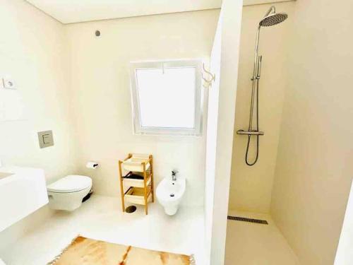 ein Bad mit einem WC, einem Fenster und einer Dusche in der Unterkunft Casa de Praia - Almograve in Almograve