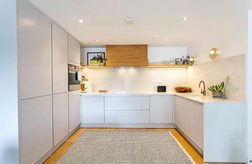 a kitchen with white cabinets and a rug at Penthouse in Luton