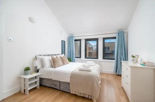 a white bedroom with a bed and a window at Penthouse in Luton