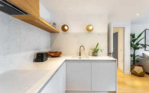 a white kitchen with a sink and a counter top at Penthouse in Luton