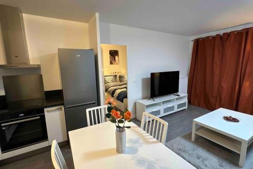 a living room with a table and a kitchen with a television at Appartement Cozy - Quartier résidentiel in Melun