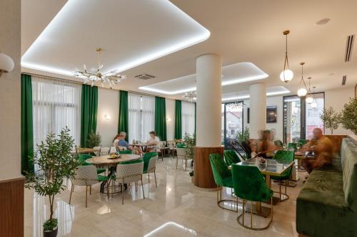 ブドヴァにあるHotel Diplomatの緑の椅子とテーブル、人々が並ぶレストラン