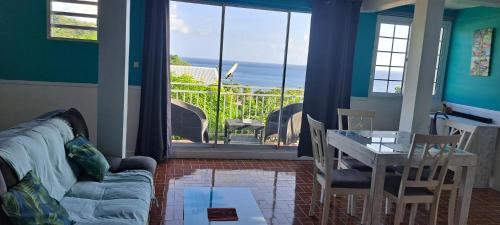 sala de estar con sofá, mesa y balcón en Evasion Nord Caraïbe vue mer -plage 5 mn à pieds en Le Carbet