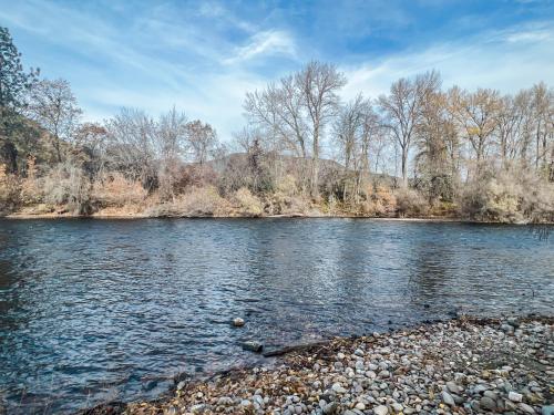 a river with a rocky shore with trees in the background at Waterfront River Apartments in Rogue River
