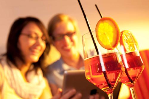a man and a woman with a laptop and a drink at Essential by Dorint Berlin-Adlershof in Berlin