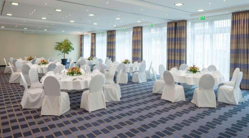 a banquet hall with white tables and chairs at Essential by Dorint Berlin-Adlershof in Berlin