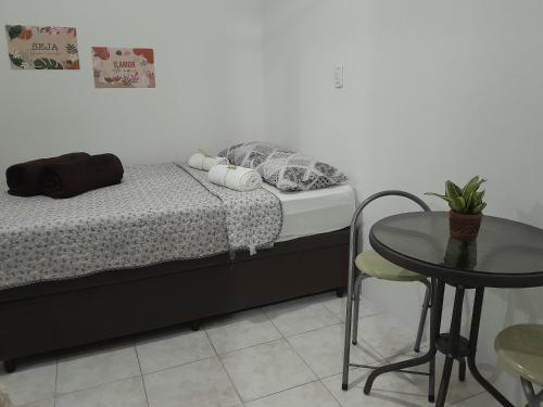 1 dormitorio con mesa, cama, mesa y silla en Suite Privativa Lar e Aconhego, en Maricá
