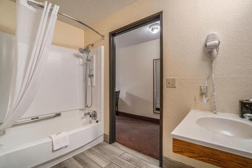 een badkamer met een bad, een wastafel en een douche bij Days Inn & Suites by Wyndham Traverse City in Traverse City