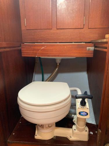 a bathroom with a toilet under a wooden cabinet at Pāvilostas_laivas in Pāvilosta