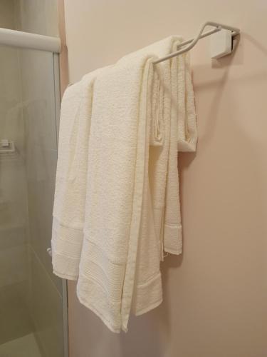 uma toalha branca pendurada num cabide na casa de banho em Villa Ida, Suíte 01 c/ copa p/ casal em Serra Negra