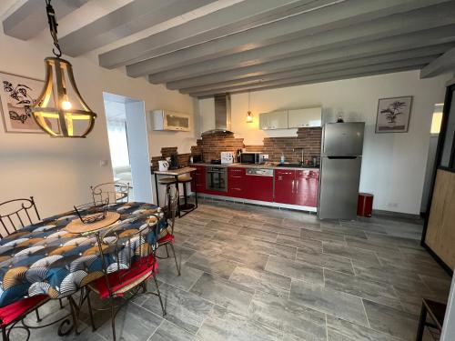 une cuisine et une salle à manger avec une table et une cuisine avec des placards rouges dans l'établissement Les maisons du phare, à Berville-sur-Mer