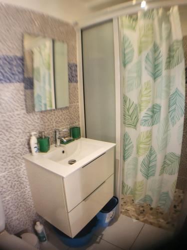 a bathroom with a white sink and a shower curtain at bungalow Bô Sicrié in Le Moule