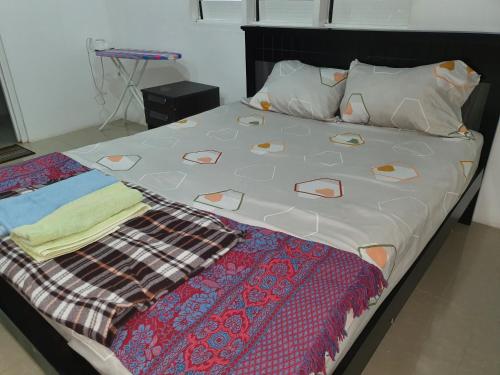 ein großes Bett mit einer Decke und Kissen darauf in der Unterkunft Single Room with Shared Kitchen and Living Room in Suva