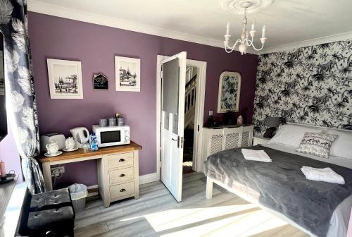 um quarto com paredes roxas, uma cama e um micro-ondas em HighTree House em Cork