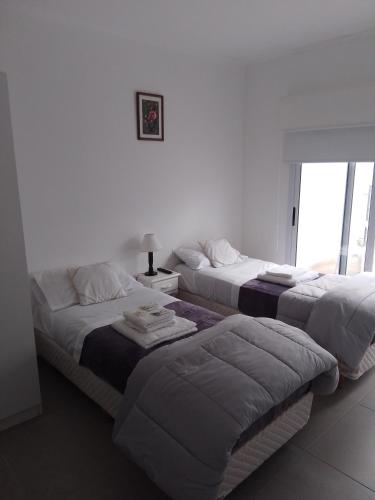 2 Betten in einem weißen Zimmer mit Fenster in der Unterkunft cel2245508464 Céntrico in Dolores
