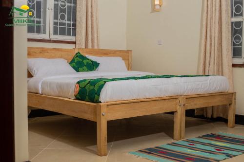 Cette chambre comprend un lit avec un cadre en bois. dans l'établissement Miika Guest House, à Entebbe