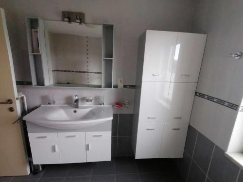 Baño blanco con lavabo y espejo en Huis Rochelle, en Bredene